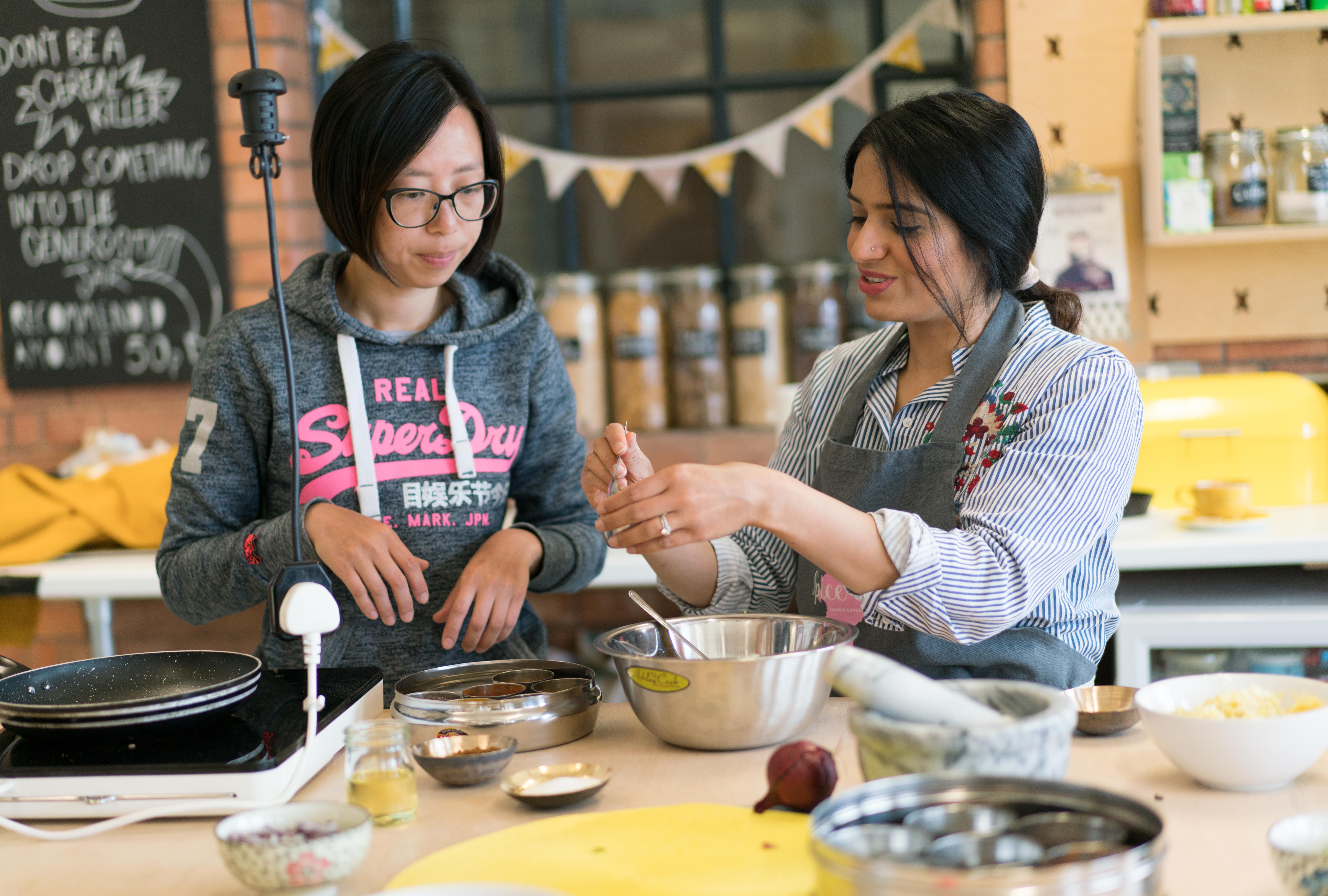 Monica teaching a student at The Spice Club cookery class