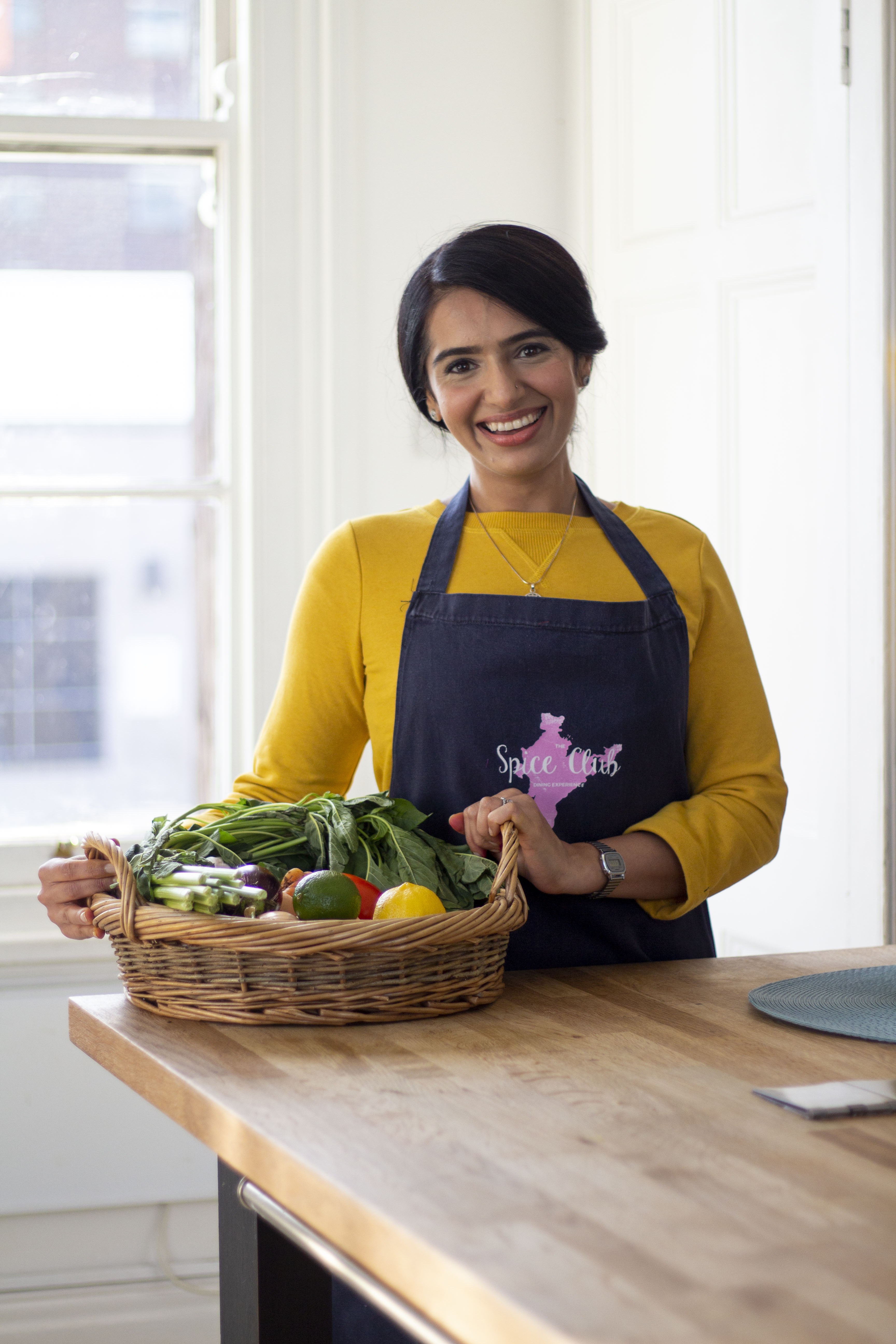 Monica Sawhney Haldar, Indian cookery teacher and chef, holding a basket of fresh vegetables
